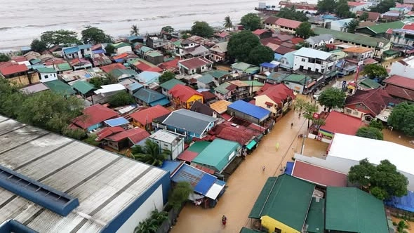 Vehicles traveling through floodwater on a submerged road lined with palm trees in Zambales